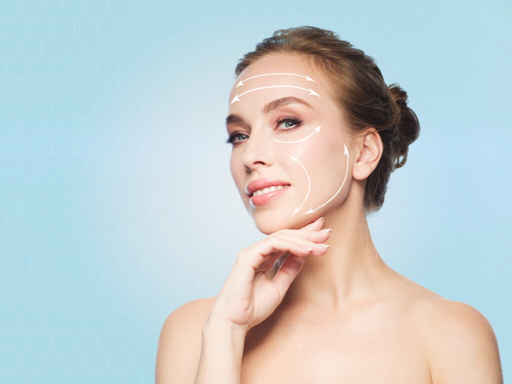 beauty, people, plastic surgery, anti-age and health concept - beautiful young woman touching her face over blue background